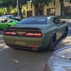 the rear end of a green sports car parked next to other cars in a parking lot