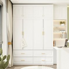 a kitchen with white cupboards and an island in front of the window, next to a potted plant