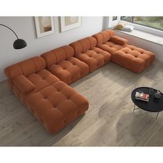 an orange sectional sofa sitting on top of a hard wood floor next to a window