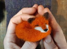 a person holding a small stuffed animal in their hands with the fox on it's face