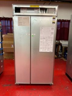 a silver refrigerator freezer sitting inside of a room next to other appliances and boxes