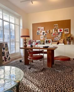 a living room filled with lots of furniture and pictures on the wall behind a glass table