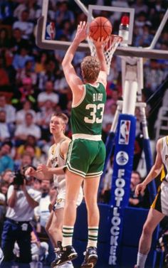 a basketball player jumping up to dunk the ball in front of other players and fans