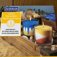 two candles sitting on top of a wooden box next to shells and seashells