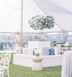 a white couch sitting on top of a lush green field next to a tall vase filled with flowers