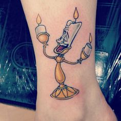 a cartoon character holding a lit candle tattoo on the foot