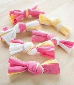 several small bows are lined up on a table top, one is pink and the other is yellow