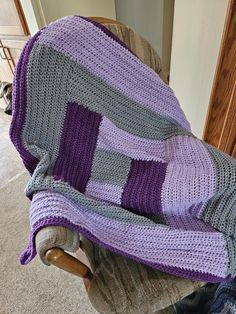 a crocheted blanket sitting on top of a rocking chair next to a person's leg