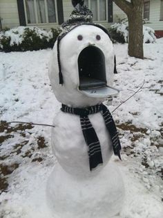 a snowman with a hat and scarf around it's neck standing in the snow