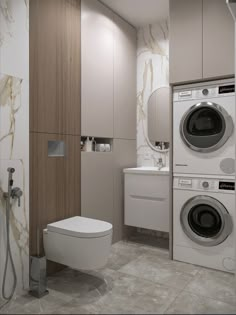 a washer, dryer and toilet in a bathroom with marble flooring on the walls