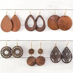 several pairs of wooden earrings hanging on a white wall with wood circles and tears