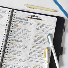 a notebook with some writing on it next to two pens and a pencil in front of it