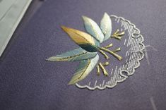 a close up of a purple cloth with embroidered leaves on it