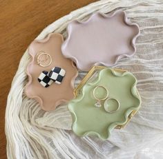 three pieces of jewelry sitting on top of a white cloth covered table next to each other