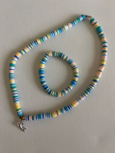 a multicolored beaded necklace on a white surface with a star charm hanging from it