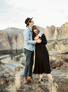 a man and woman standing next to each other in the mountains