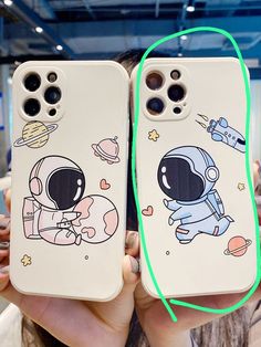 two phone cases with an astronaut and spaceman on them, one being held up to the camera