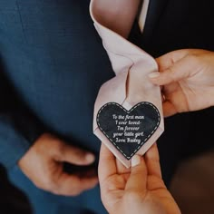 a person wearing a suit and tie holding a heart shaped ornament in their hands