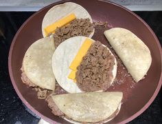 three tortillas with cheese and ground beef are in a pan on the stove