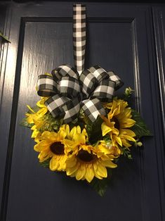 a sunflower wreath hanging on the front door with black and white checkered ribbon