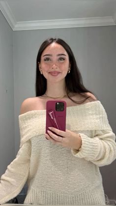 a woman taking a selfie with her phone in front of her face and wearing an off the shoulder sweater