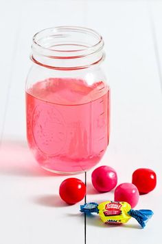 a jar filled with pink liquid next to candy