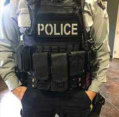 a police officer is standing with his back to the camera, wearing black pants and vests