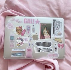 an open laptop computer sitting on top of a pink blanket covered in stickers and magnets