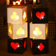 four illuminated cubes with playing cards and hearts on them, sitting on a table