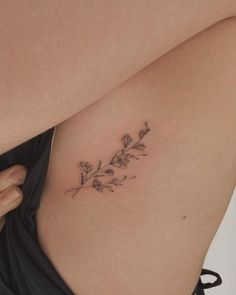 a woman's stomach with a small flower tattoo on her left side ribcage