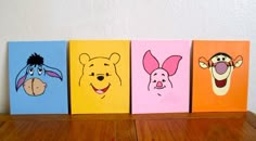 winnie the pooh and friends painted on canvases sitting on top of a wooden table