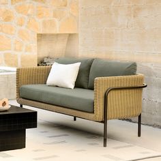 a couch sitting on top of a white rug next to a table and chair in front of a stone wall