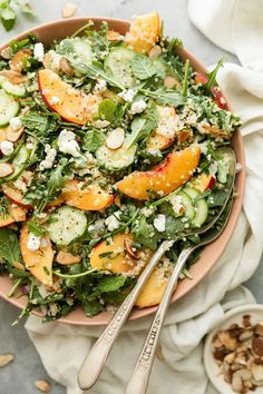 a salad with oranges, cucumbers and almonds in a pink bowl