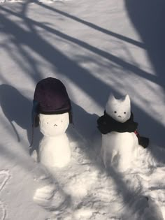 two snowmen with hats on standing in the snow