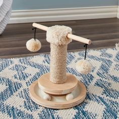 a cat scratching post with two balls on it and a wooden stick sticking out of the top