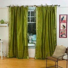 a chair sitting in front of a window with green curtains