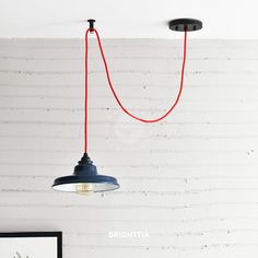 two lights hanging from the ceiling in a room with white brick wall and red string