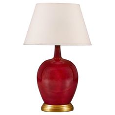 a red table lamp with a white shade on the base and a gold plated base