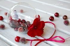 a glass ornament filled with red and white candies on top of a wooden table