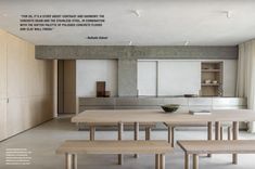 an empty table and benches in a room with large windows, cabinets, and cupboards