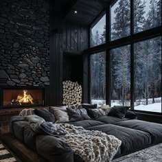 a living room filled with lots of furniture next to a window covered in blankets and pillows