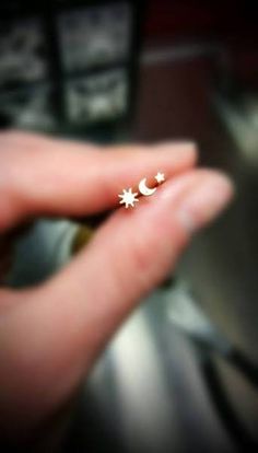 a person's hand holding a tiny star and moon ring