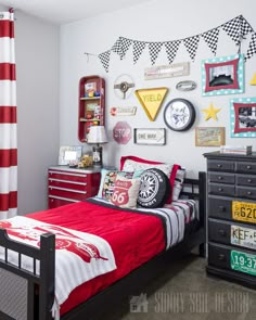 a bedroom decorated in red, white and blue with lots of pictures on the wall