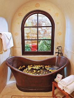 a bathtub filled with lots of yellow flowers next to a window in a bathroom