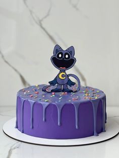 a purple cake with sprinkles and a cartoon character on top, sitting on a white plate