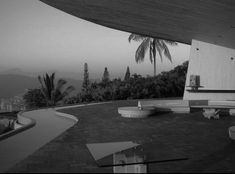 a black and white photo of an outdoor area with benches, tables and palm trees