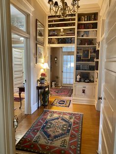 a living room filled with furniture and a chandelier hanging from the ceiling over a doorway