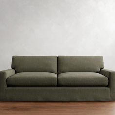 a couch sitting on top of a hard wood floor next to a white wall in an empty room