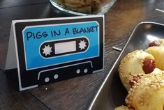 there is a sign that says pigs in a blanket next to a plate of food