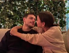 a man sitting next to a woman on top of a couch in front of a tree